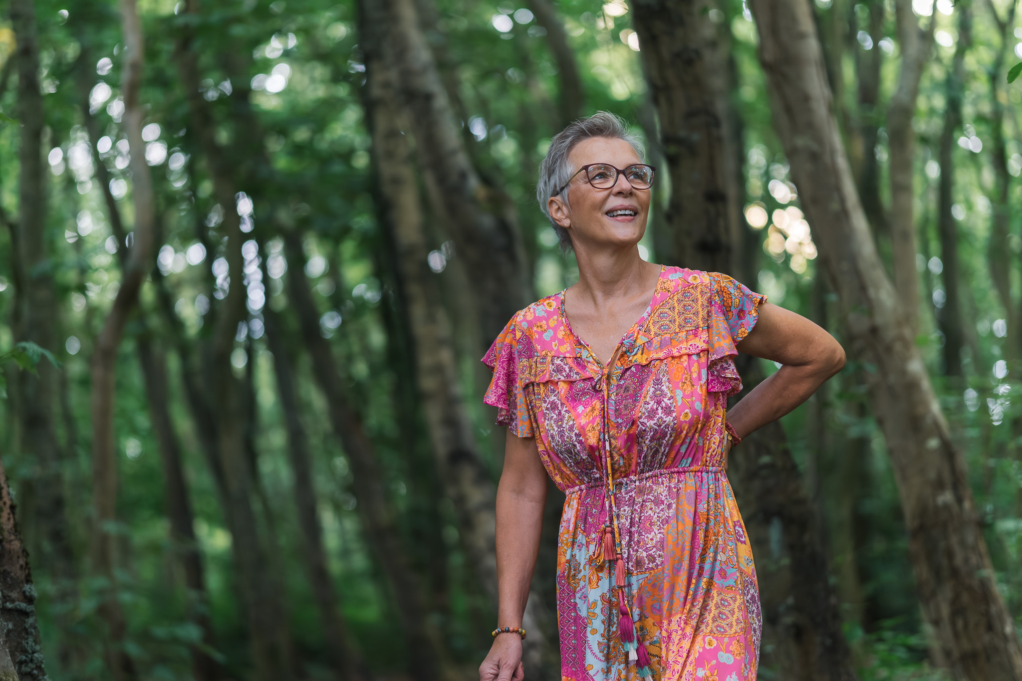 Portret van vrouw in kleurrijke jurk in groene bosomgeving