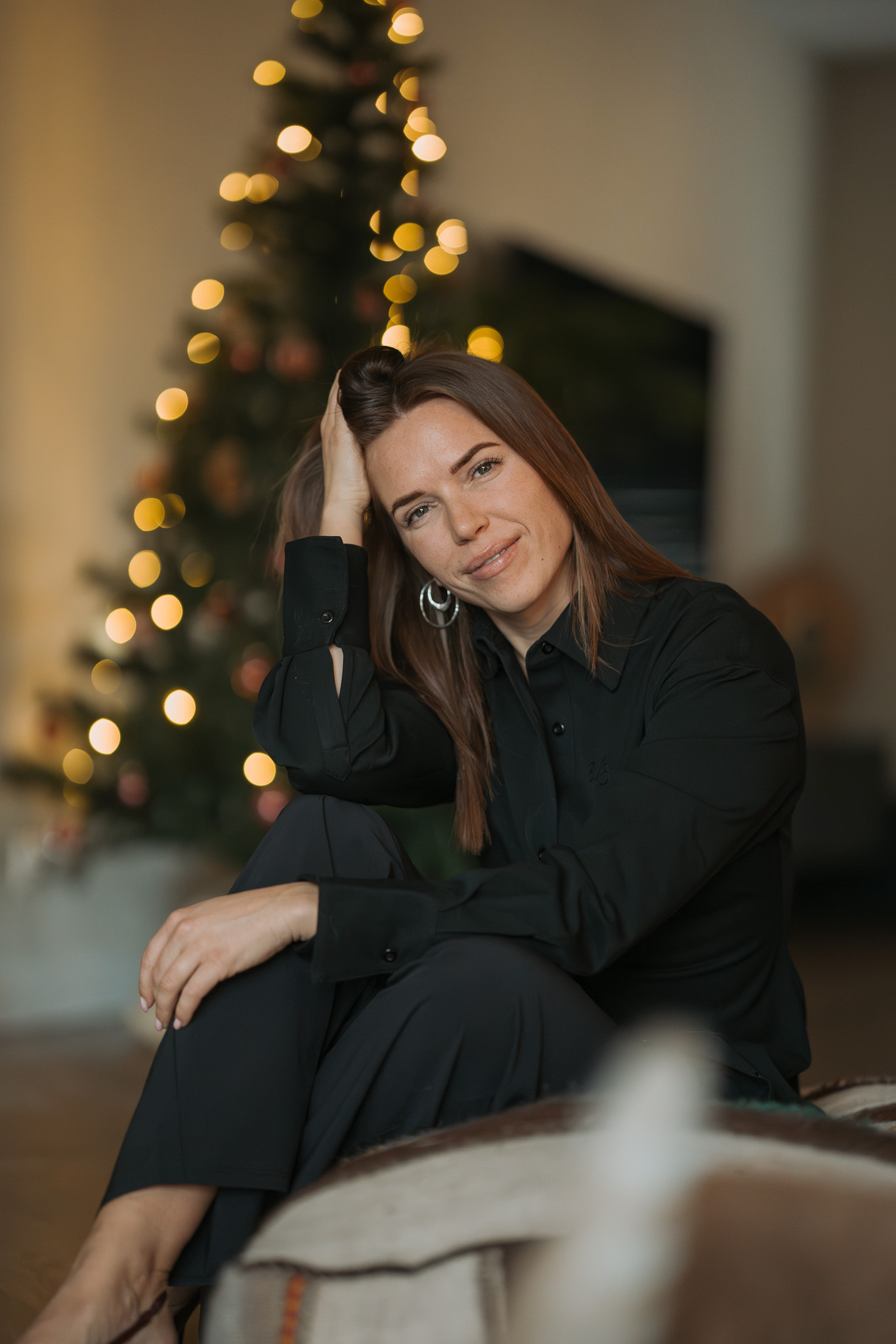 Portret van vrouw bij kerstboom met warm binnenlicht